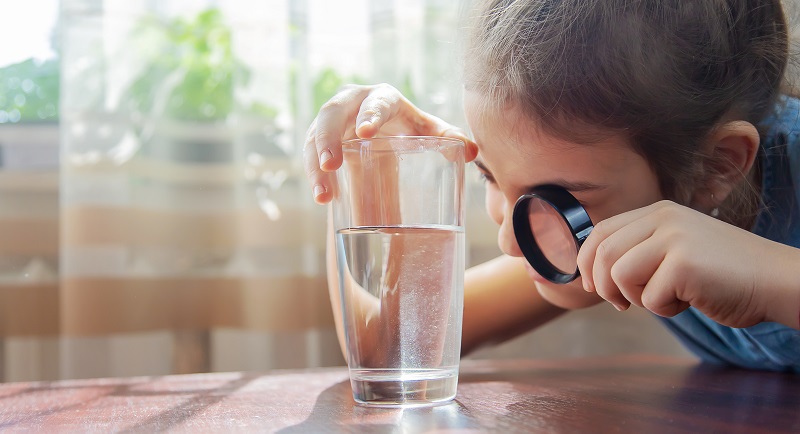The,child,examines,the,water,with,a,magnifying,glass,in